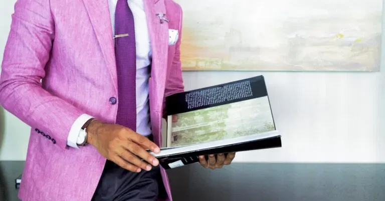 A Businessman In A Pink Suit Holding A Book, Symbolizing Success And Professionalism.