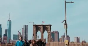 View Of The Iconic Brooklyn Bridge With Pedestrians And Manhattan Skyline In New York City.