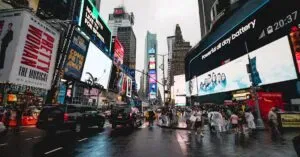 Night View Of Times Square In Nyc With Illuminated Billboards And A Lively Crowd.