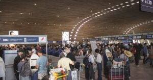 Crowded Airport Terminal With Travellers In Line. Indoor Setting With Modern Architecture.