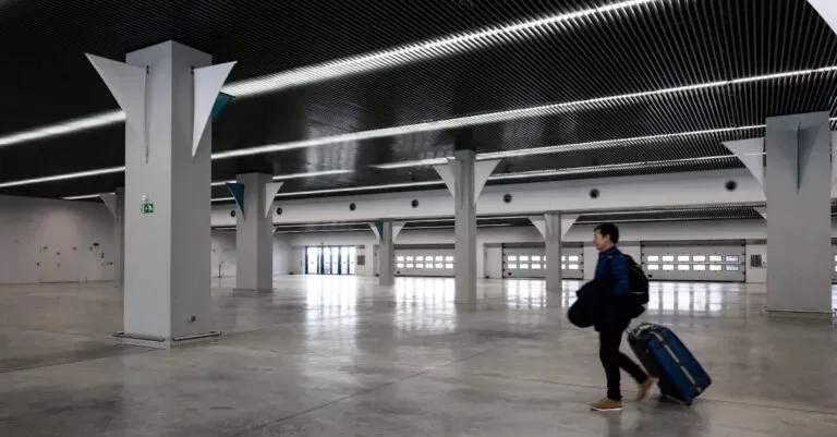 A Man With Luggage Walking Through A Spacious, Modern, Empty Airport Hall.