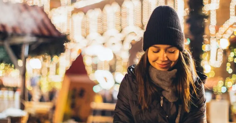 New York Blogs | Articles | News | Tips &Amp; Tricks | Video | Faq | Information | Infograph. 35 June 11, 2026 Happy Young Female In Black Warm Jacket And Hat Looking Down And Smiling While Sitting On Wooden Bench Among Christmas Decorations In Night City