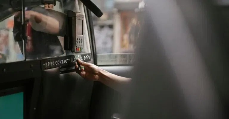 A Passenger Makes A Payment Using A Card In A Taxi With A Handheld Payment Terminal.