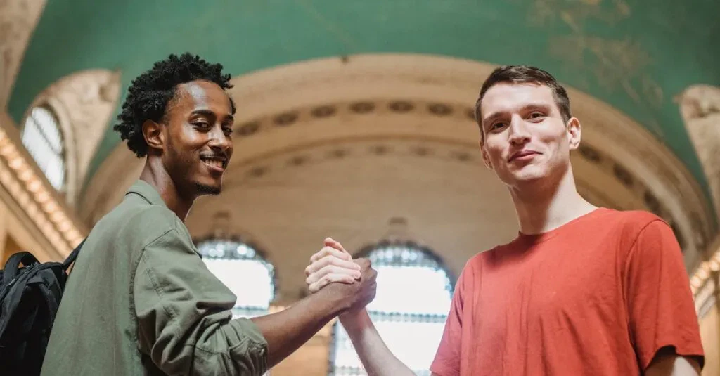 Bus Grand Central To Newark: 10 Smart Tips To Make Your Trip Easy 6 April 15, 2026 From Below Of Positive Young Multiethnic Male Friends In Casual Clothes Smiling And Looking At Camera While Shaking Hands In Spacious Aged Arched Building