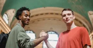 New Jersey Articles &Amp; News 3 April 14, 2026 From Below Of Positive Young Multiethnic Male Friends In Casual Clothes Smiling And Looking At Camera While Shaking Hands In Spacious Aged Arched Building
