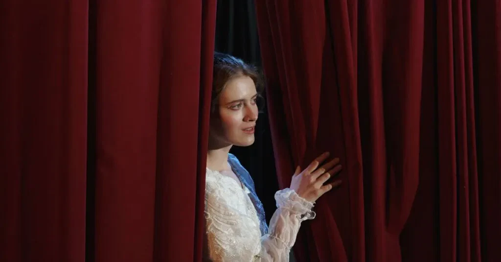 A Woman In Costume Peeks Through Red Theater Curtains In A Dramatic Scene.
