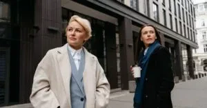 Two Women In Stylish Professional Attire Walking In A Modern Urban Environment.