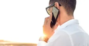 Luxury Car &Amp; Limo Services Articles &Amp; News 4 June 10, 2026 Man Outdoors In Morocco Talking On Smartphone, Wearing Sunglasses And White Shirt, Backlit By Sunset.