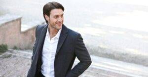 Luxury Car &Amp; Limo Services Articles &Amp; News 1 May 15, 2026 Confident Man In A Suit Smiling While Walking Outdoors, Showcasing Fashion And Style.