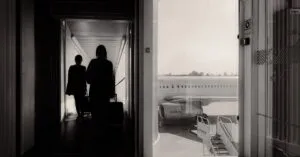 Silhouetted Travelers Walking Through An Airport Jet Bridge Toward An Airplane, Conveying A Travel Mood.