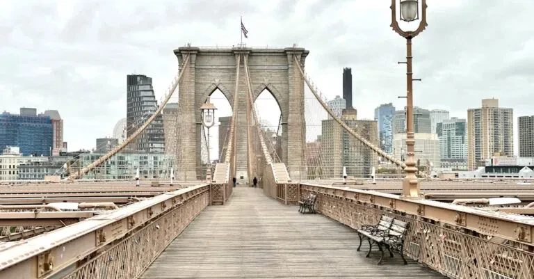 Iconic Brooklyn Bridge View With Manhattan Skyline In The Background, Featuring Classic Architecture.