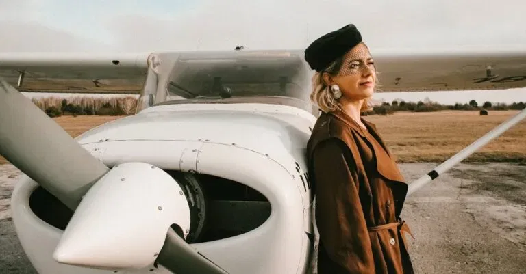 Elegant Woman With Blond Hair Standing By Small Aircraft In Daylight