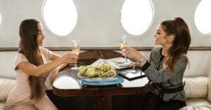 Two Women Enjoying A Toast On A Private Jet, Symbolizing Luxury Travel And Elegance.