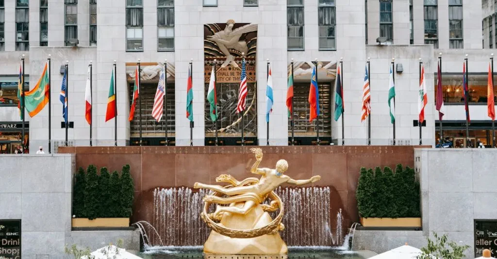 Golden Prometheus Statue Located Near Entrance Of Rockefeller Center With Flags On Street In New York City In Modern District