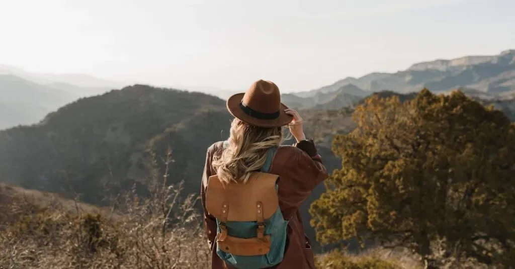Woman Wearing A Backpack Hiking In Mountainous Countryside, Enjoying The Scenic View.