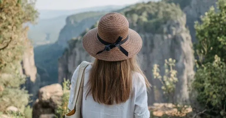 A Woman In A Hat Enjoys The Breathtaking View Of A Canyon, Capturing The Essence Of Adventure And Travel.