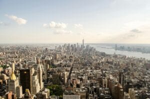 A Breathtaking Aerial View Of New York City Showcasing The Iconic Skyline Over The River Under A Clear Sky.
