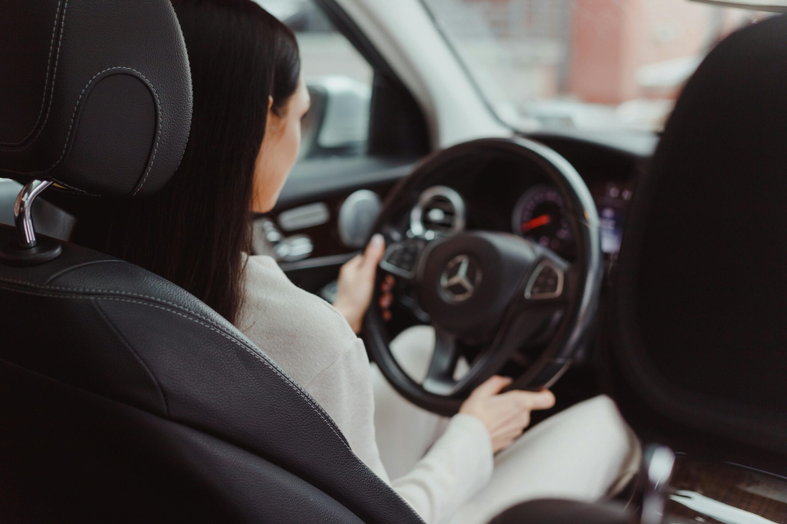 Rear View Of A Woman Driving A Mercedes Benz, Focusing On The Interior And Steering Wheel.