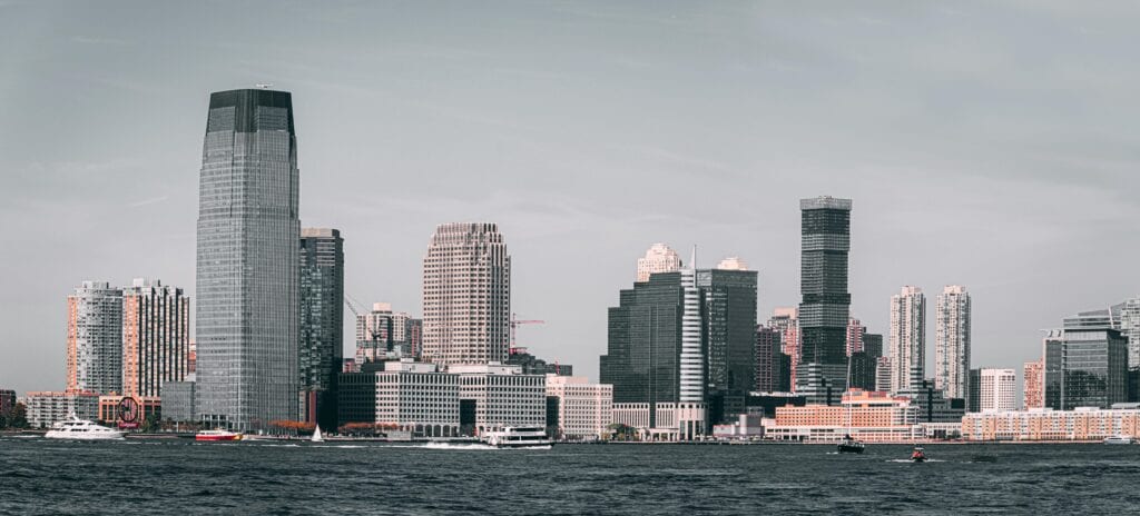 A Breathtaking View Of Jersey City'S Skyline From Across The Hudson River With Modern Skyscrapers And Waterfront Buildings.