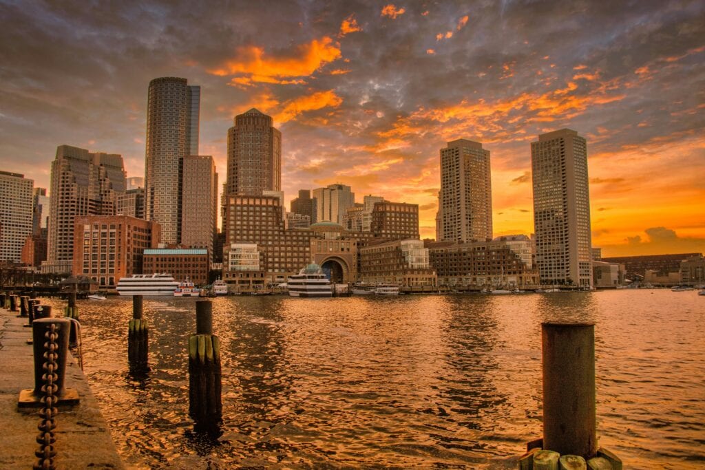Stunning Sunset Over Boston'S Iconic Skyline Reflecting In The Harbor Waters.