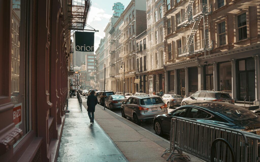 Top Nyc Cadillac Limo Services In 2026: Why A Cadillac Black Car Still Beats The Chaos 1 April 12, 2026 Sunlit Street In Manhattan With Cars And Buildings, Capturing The Essence Of Nyc Architecture.