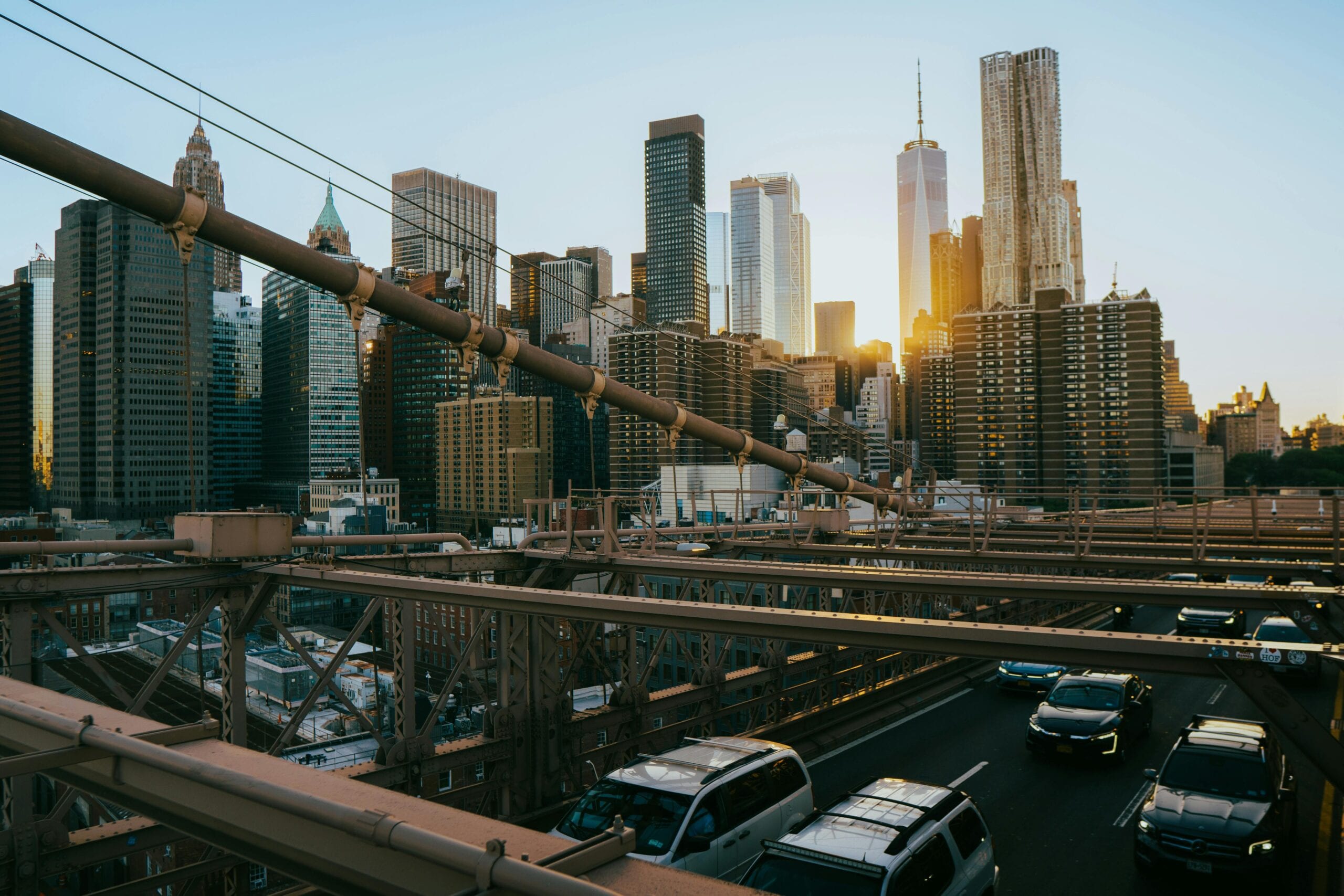 Captivating Sunset View Of Manhattan Skyscrapers From The Iconic Brooklyn Bridge In New York City.