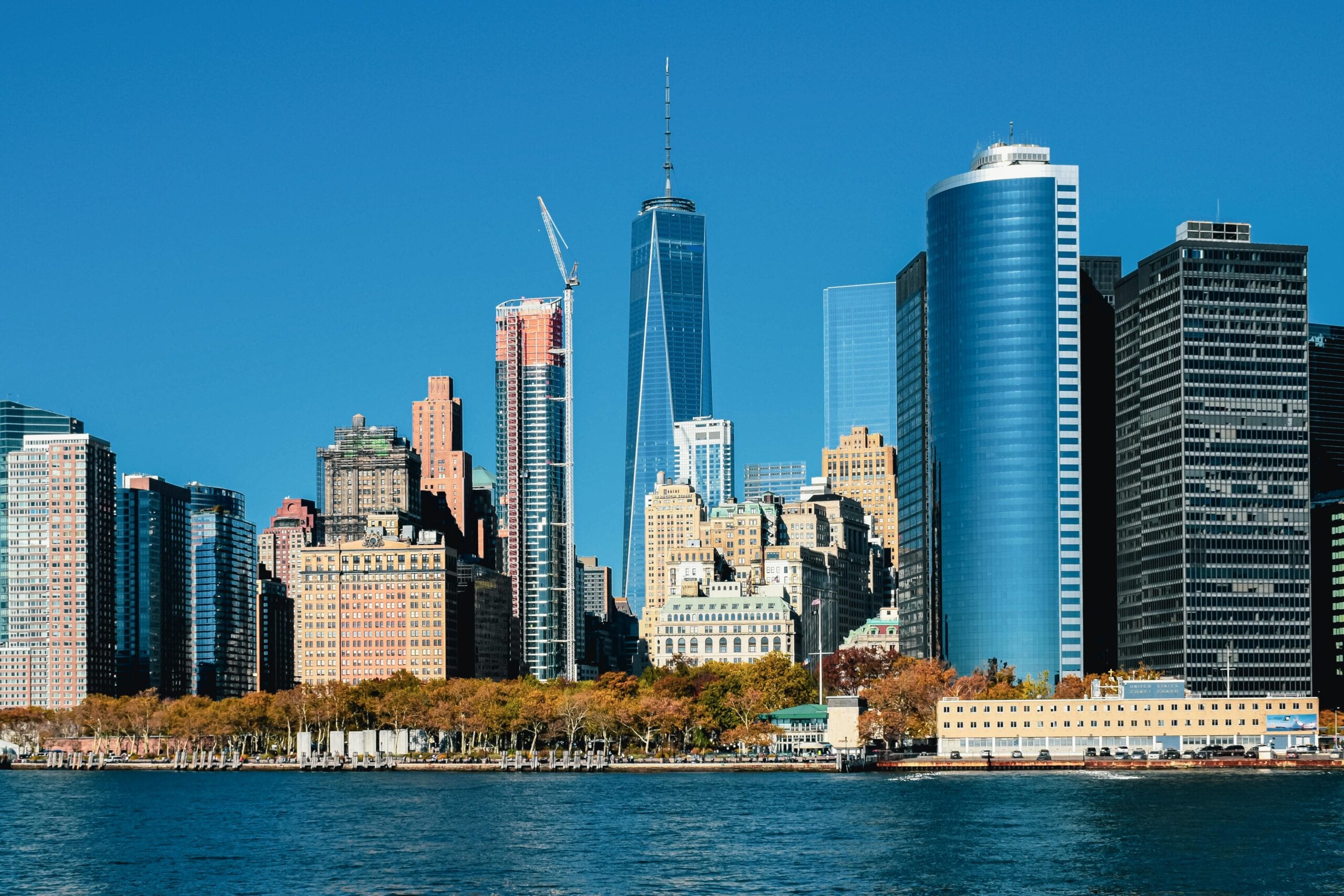 Captivating View Of The Lower Manhattan Skyline With Iconic Skyscrapers Under A Clear Blue Sky.