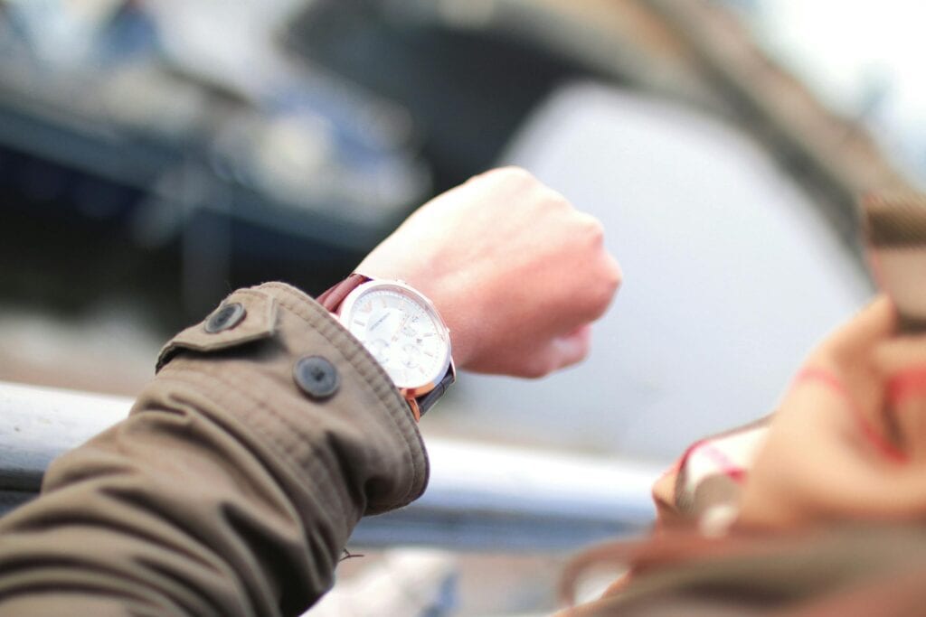 A Person Checks Their Wristwatch In A Hurried Outdoor Setting, Emphasizing Time Management.