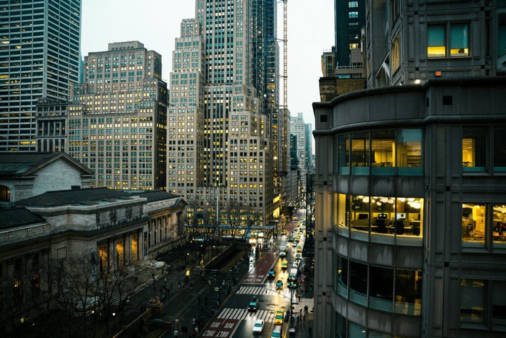 A Bustling Street Scene In New York City With Iconic Skyscrapers And Evening Lights.