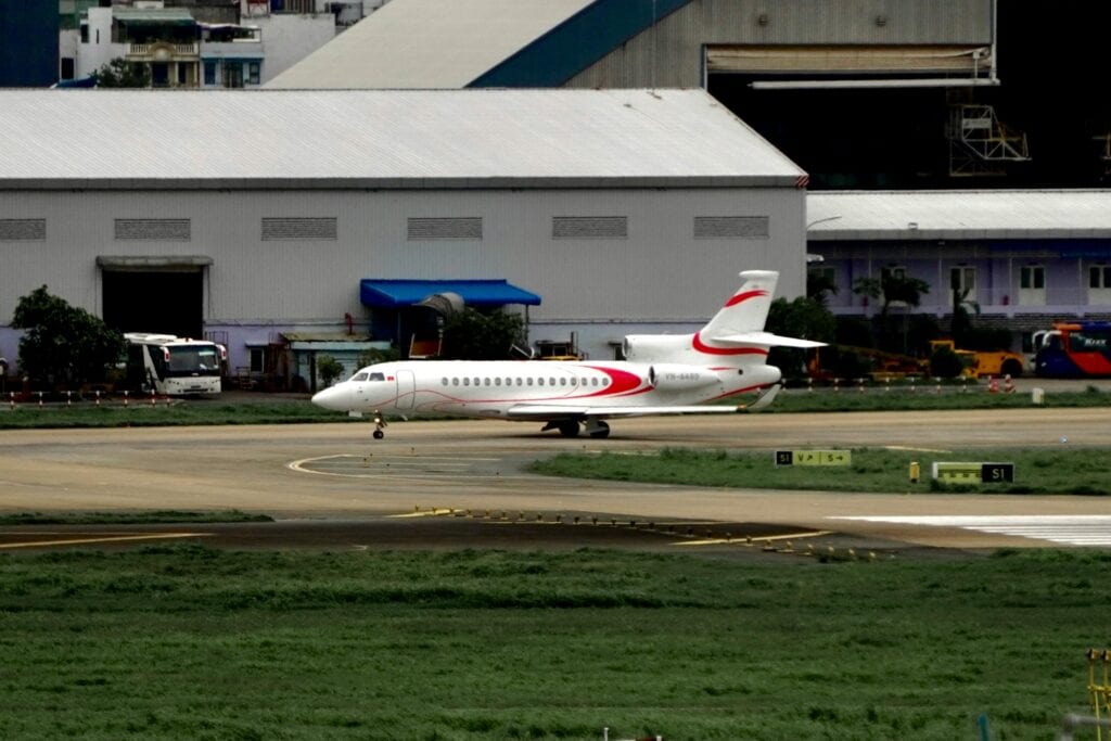 A Private Jet Positioned On An Airport Runway Near Hangars.