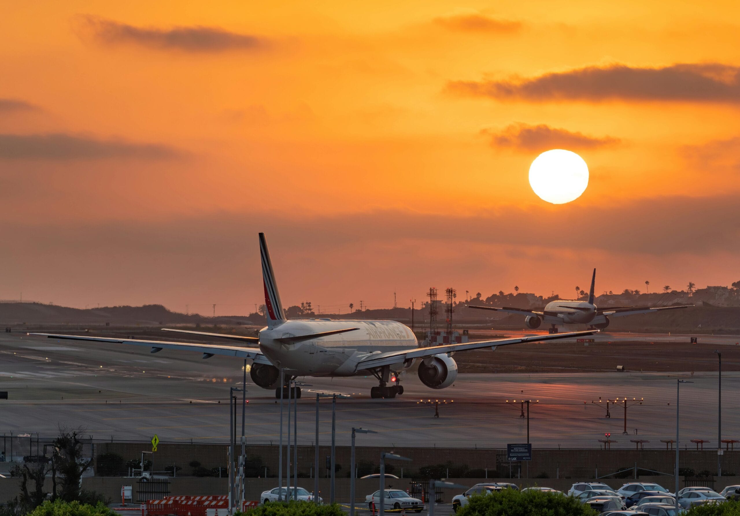A Stunning View Of Airplanes Taxiing At Los Angeles Airport With A Vibrant Sunset In The Background.