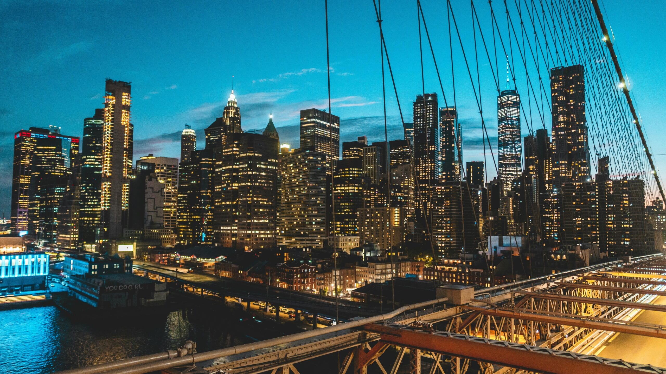 Panoramic View Of New York City Skyline At Twilight From Brooklyn Bridge, Showcasing Modern Skyscrapers.
