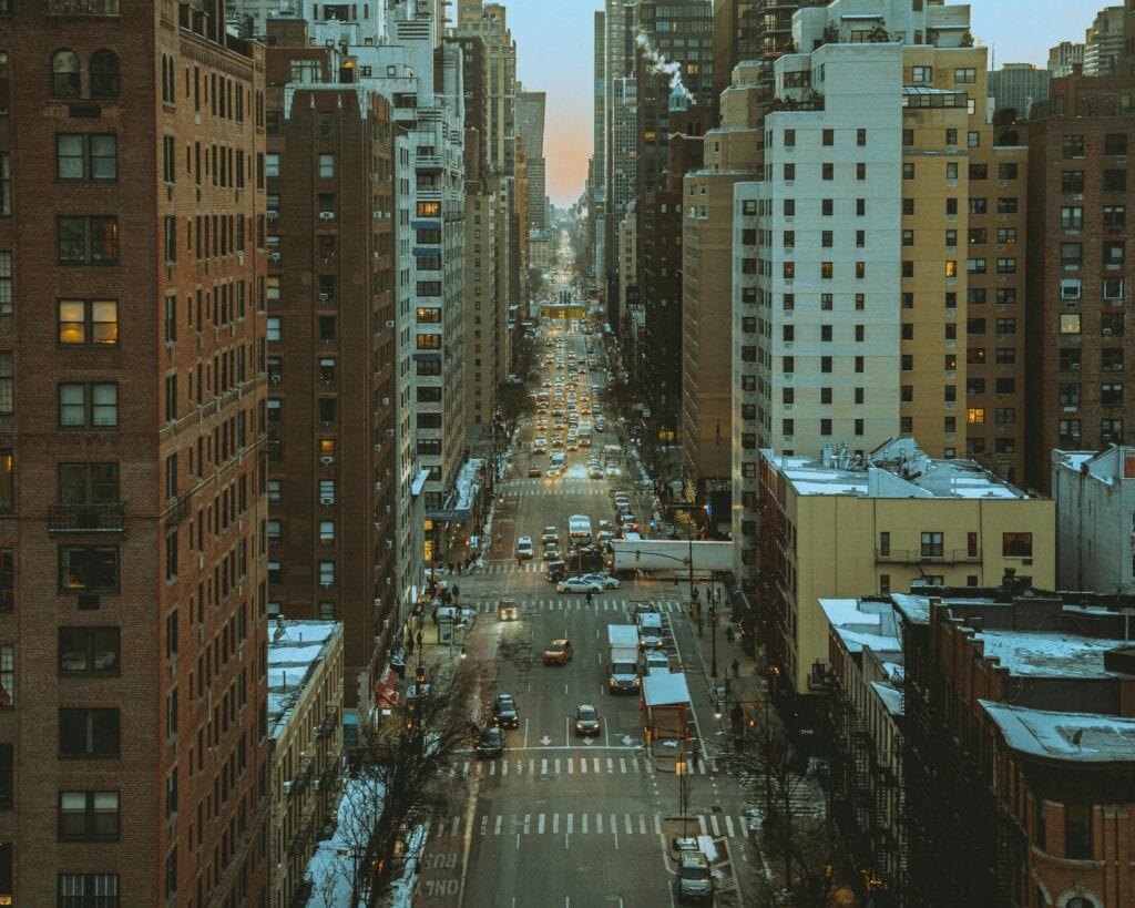 Aerial View Of A Busy New York City Street Lined With Skyscrapers During Dusk, Capturing Urban Life.