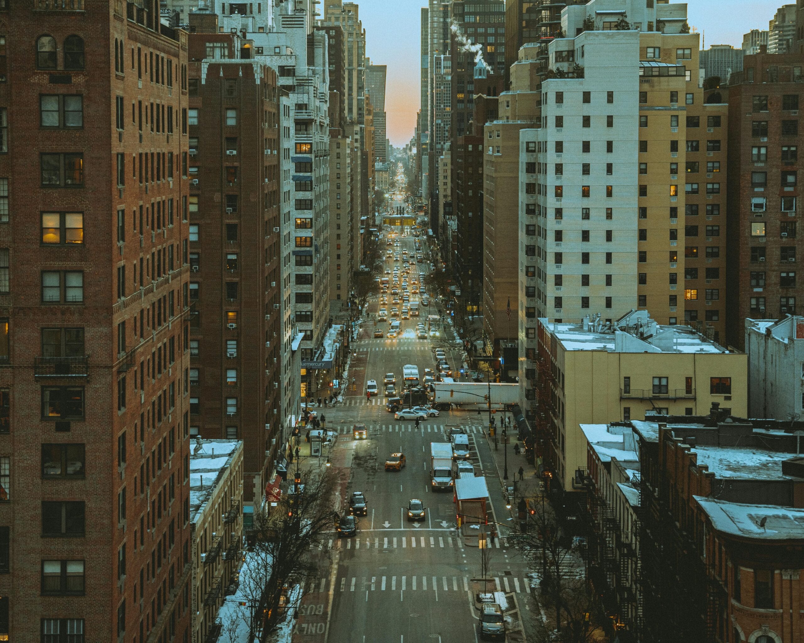 Aerial View Of A Busy New York City Street Lined With Skyscrapers During Dusk, Capturing Urban Life.
