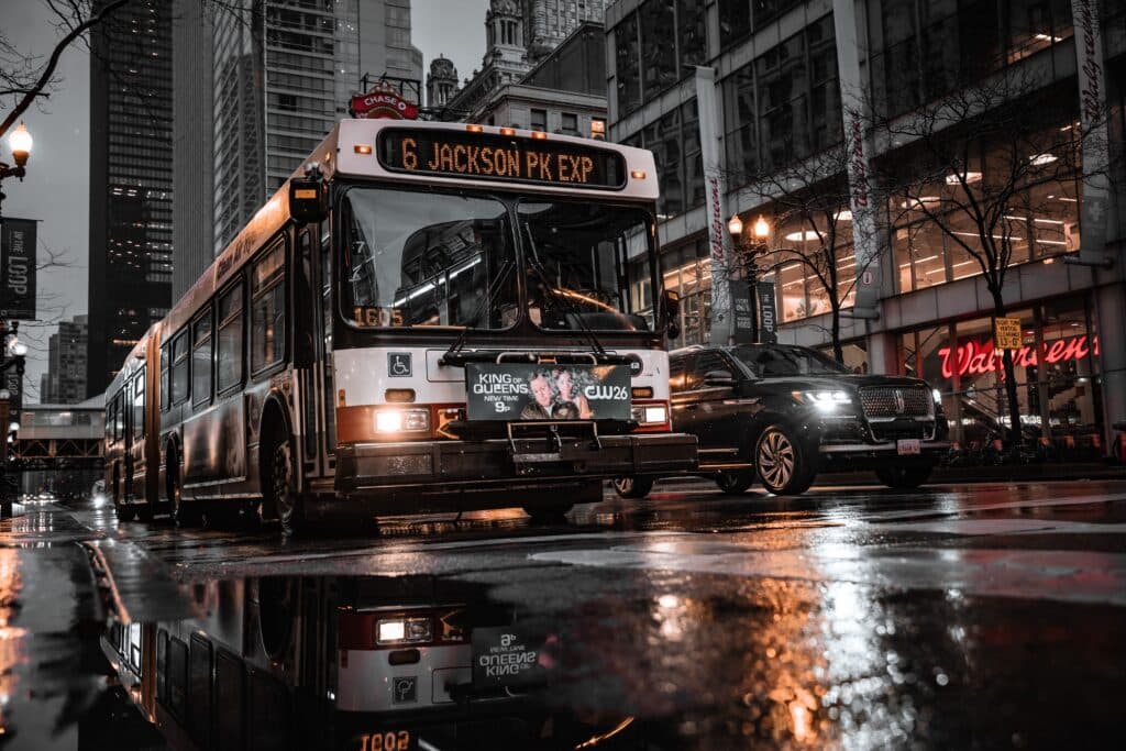 City Bus And Cars Reflected On Wet Street In Chicago'S Urban Landscape At Night.