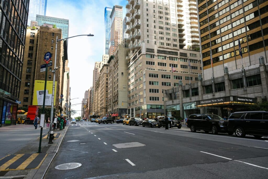 Urban Cityscape Of Midtown Manhattan With Skyscrapers, Vehicles, And Pedestrians.