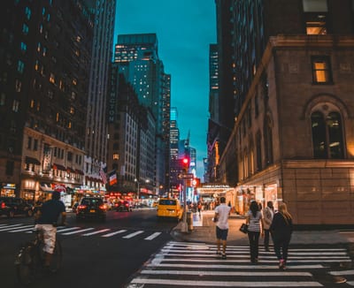 Busy Streets Of New York City Illuminated At Night With Vibrant Lights And Bustling Traffic.