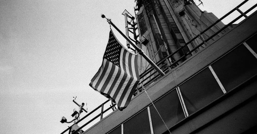 Black And White Image Of American Flag On A Skyscraper In New York City, Emphasizing Urban Architecture And Patriotism.