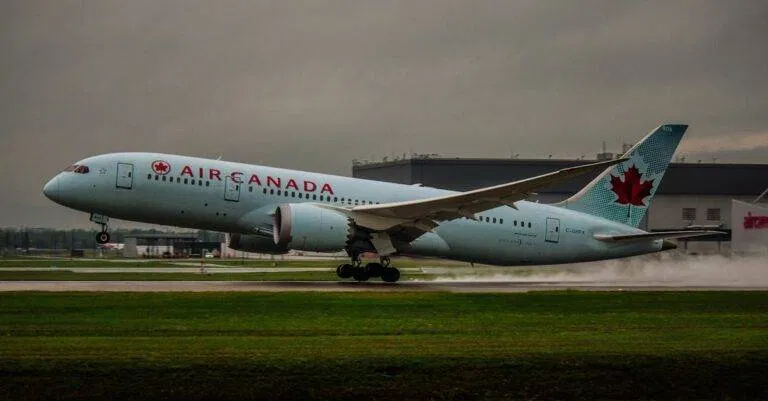 An Air Canada Airplane Touching Down On A Runway Under Cloudy Skies, Creating A Dynamic Travel Scene.
