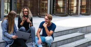 Three Young Professionals Having A Friendly Chat While Sitting On Outdoor Steps.