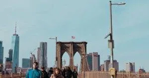 View Of The Iconic Brooklyn Bridge With Pedestrians And Manhattan Skyline In New York City.