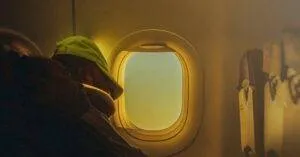 A Person Rests Peacefully By An Airplane Window, Warm Light Filtering Through.