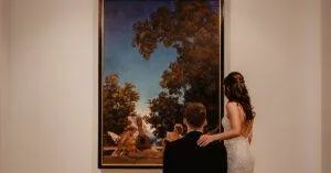 Elegant Couple Viewing A Painting In A Modern Museum, Capturing The Essence Of Art Appreciation.