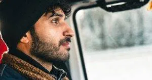 Man With A Beard In A Warm Jacket Driving Through A Snowy Landscape, Showcasing Adventure And Travel.