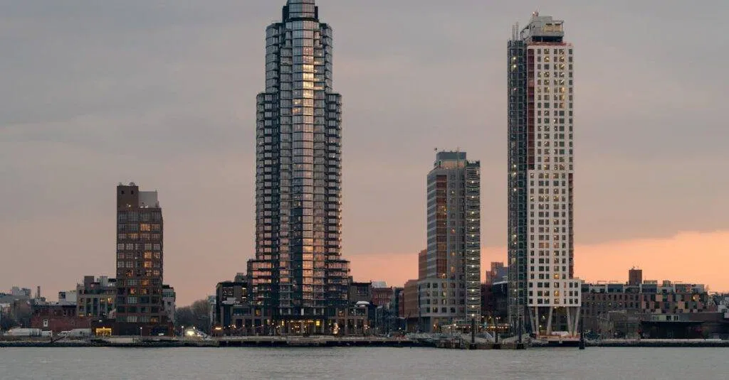 A Tranquil View Of New York City Skyscrapers At Sunset With Reflections On The East River.