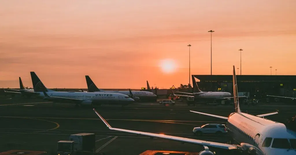 A Serene View Of Parked Airplanes At An Airport With A Beautiful Sunset In The Background.