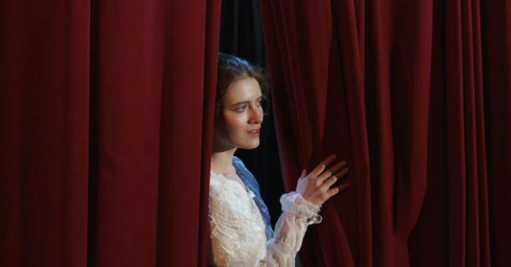 A Woman In Costume Peeks Through Red Theater Curtains In A Dramatic Scene.
