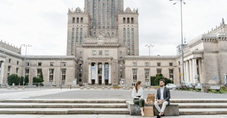 Two colleagues enjoy lunch on steps of Warsaw's Palace of Culture and Science.