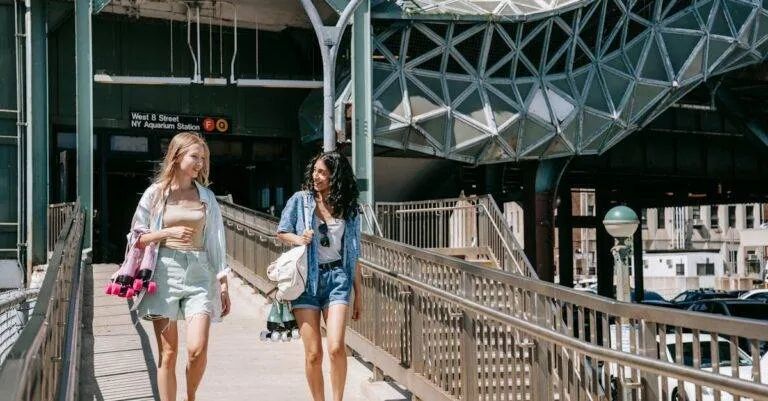 Two Women Walk And Chat At Ny Aquarium Station On A Sunny Summer Day.