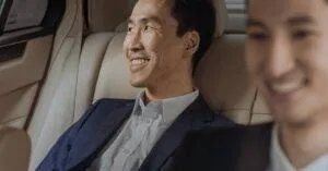 Two Men In Formalwear Enjoying A Comfortable Ride In A Luxury Car, Smiling.